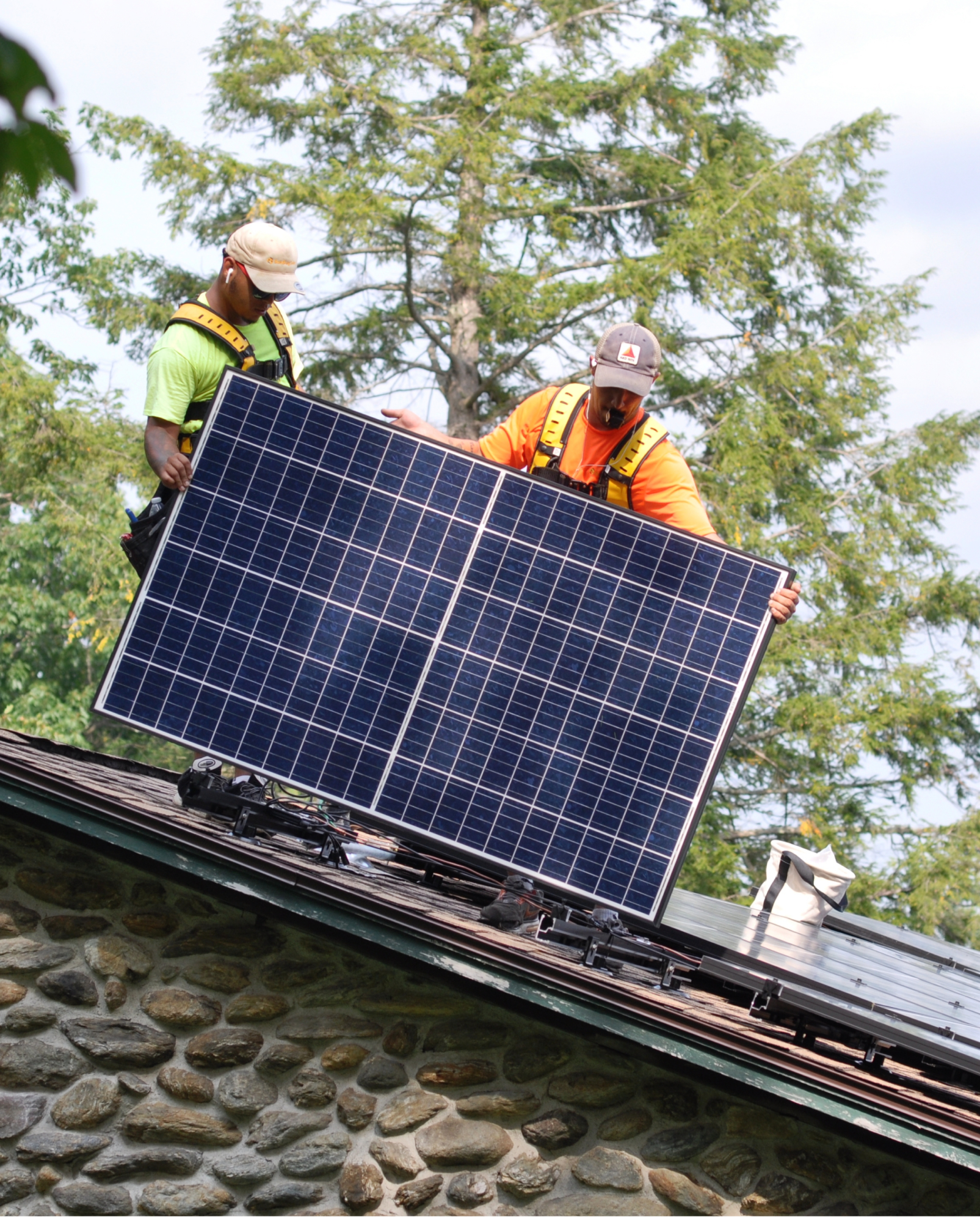 two men working on roof carrying solar panel